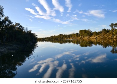 Interesting clouds reflected in the calm Murray RIver water on a bend near outback Mildura in landscape orientation