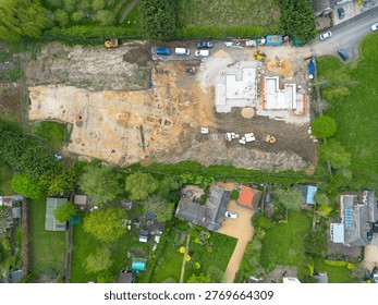 Interesting drone UAV top down view of a small, new housing development in Cambridgeshire, UK. An archeological dig is seen on the left site of the building site, being cleared before new homes are being built.