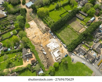Interesting drone UAV top down view of a small, new housing development in Cambridgeshire, UK. An archeological dig is seen at the top of the building site, being cleared before new homes are being built.
