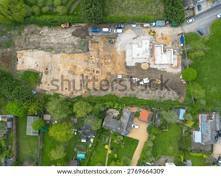 Interesting drone UAV top down view of a small, new housing development in Cambridgeshire, UK. An archeological dig is seen on the left site of the building site, being cleared before new homes are being built.