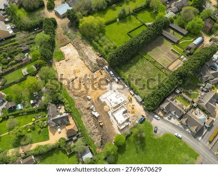 Interesting drone UAV top down view of a small, new housing development in Cambridgeshire, UK. An archeological dig is seen at the top of the building site, being cleared before new homes are being built.