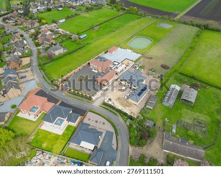 Interesting drone UAV view of a pair of very large detached houses in rural Britain. One of the mansions is complete, the other partially completed. Seem at the edge of a rural village.
