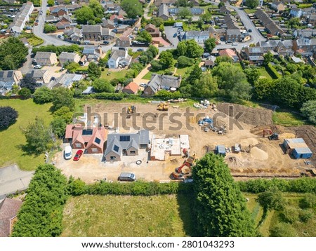 Interesting drop UAV view of a new detached bungalows being built within a small building plot in Cambridgeshire, UK. Established homes surround the site.