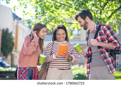 Interesting here. Joyfully smiling girl with tablet friend with boyfriend standing looking curiously next to coffee - Shutterstock ID 1780062725