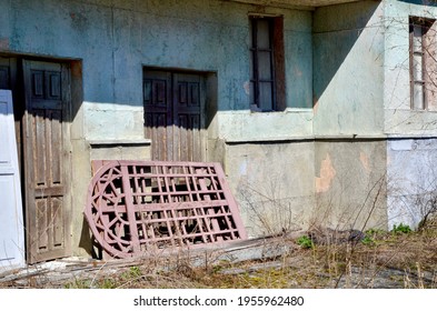 Interesting Ruined Old Building. The Red Gate Lies On The Porch Of An Old Building. Large Balcony And Wooden Doors In The Building. An Old Abandoned House. Abandoned Film Studio.