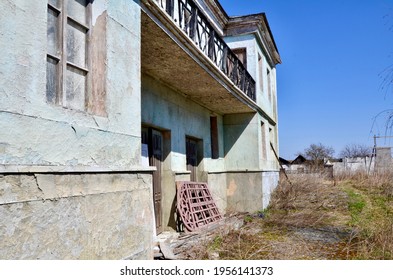 Interesting Ruined Old Building. The Red Gate Lies On The Porch Of An Old Building. Large Balcony And Wooden Doors In The Building. An Old Abandoned House. Abandoned Film Studio.