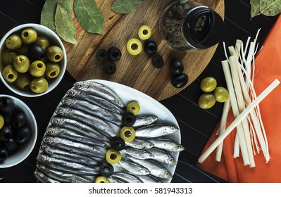 Interesting serving on the table of useful, tasty little fish sprat, condiments, olives and decor. The view from the top