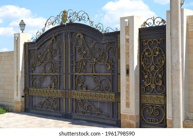 interesting wrought iron gates framed by beige columns - Powered by Shutterstock