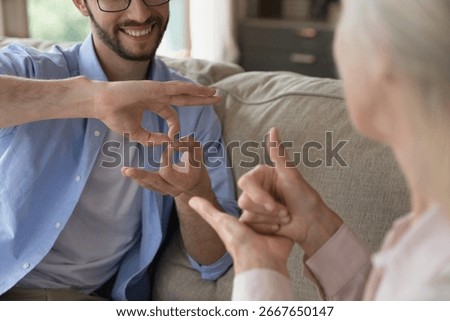 Intergenerational communication using sign language. Close up young man aged woman hold nonverbal conversation with hand gestures. Inclusive dialogue support for person with hearing disability concept