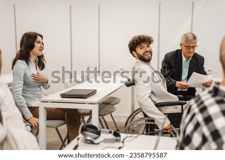 Inter-generational group of business people having business presentation at the classroom. Handicapped male business person smiling and posing for the camera
