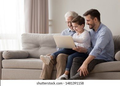 Intergenerational positive men sit on couch using looking at laptop screen having fun enjoy new app, chatting online communication, making order via internet, three generations and modern tech concept - Powered by Shutterstock