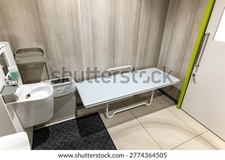 Interior of an accessible restroom featuring a multipurpose changing bench and ostomate facilities
