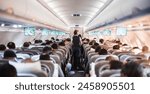 Interior of airplane with passengers on seats and stewardess in uniform walking the aisle, serving people. Commercial economy flight service concept