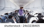 Interior of airplane with passengers on seats and female traveler walking the aisle. Commercial economy flight service concept