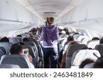 Interior of airplane with passengers on seats and female traveler walking the aisle. Commercial economy flight service concept