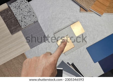 interior architect chose material samples contains gold stainless, travertine tile, roller blind drapery swatch, wooden vinyl flooring tile, interior fabric wallpaper, quartz, laminate. top view.