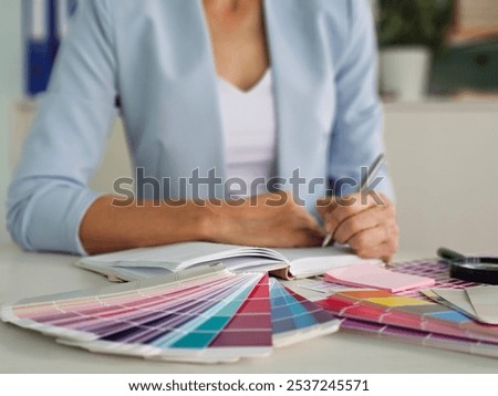 Interior architect designer at workstation table choosing various color samples art tool design with home blueprint. Creative color selection for house renovation or design