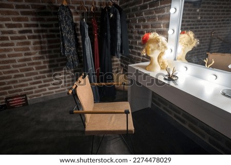 Interior of a back stage or offstage female dressing room consist of a chair, wig, mirror, wardrobe and make up stuff