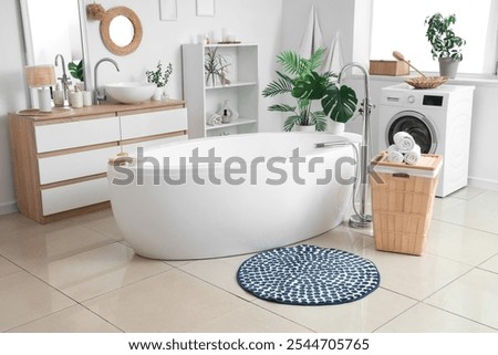 Interior of bathroom with round mat, laundry basket and washing machine