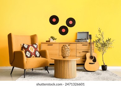 Interior of beautiful living room with chest of drawers, armchair, acoustic guitar and olive tree - Powered by Shutterstock