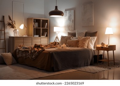 Interior of bedroom with checkered plaid on bed and glowing lamps late in evening - Powered by Shutterstock