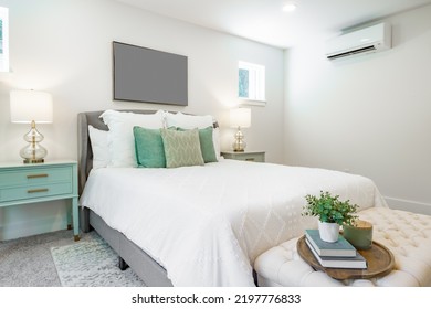 Interior bedroom with soft green and aqua colors grey bench end tables with lamps and window with green foiliage view