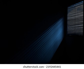 The Interior Of Blue Dark Room. Shadow Of The Rays Falling On The Wall Through The Louvers. Light From The Lamp And Shadow On The Room Wall From Roller Window Shutter. Night Club. 