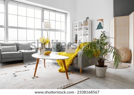 Interior of bright living room with cozy sofas near big window