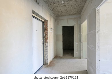 Interior of a building under construction, featuring exposed brick, unfinished walls, and open doorways