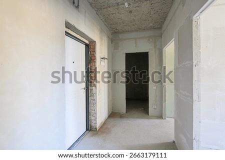 Interior of a building under construction, featuring exposed brick, unfinished walls, and open doorways