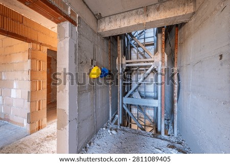 Interior of a building under construction. Unfinished elevator shaft, raw concrete and brick walls