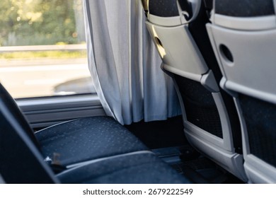 The interior of a bus features comfortable seating and privacy curtains. Sunlight filters through the fabric, creating a cozy atmosphere for travelers during their ride.