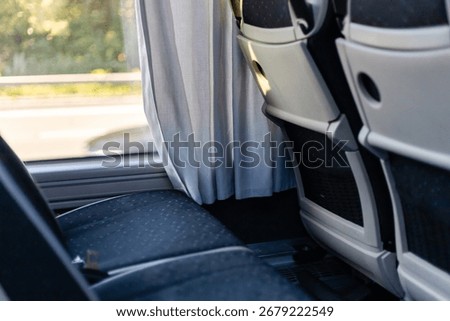 The interior of a bus features comfortable seating and privacy curtains. Sunlight filters through the fabric, creating a cozy atmosphere for travelers during their ride.