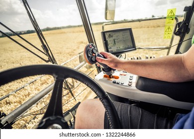 Interior cabin photo of a man sitting in modern combine harvester during harvest of wheat, sunny summer day in the Czech Republic. 