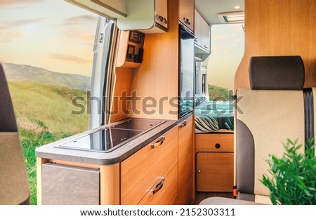 Interior of a camper van with kitchen and bed in the background