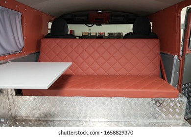 The interior of the car in the back of a van converted into a motor home for off-road and travel with a brown leather interior, a folding table and aluminum floor trim. - Powered by Shutterstock - Get 15% off with code: PIKWIZARD15