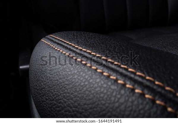 the interior of the car is\
covered with handmade genuine leather. front car seat. close up.\
High-quality stitching with gold threads and skin texture are\
visible