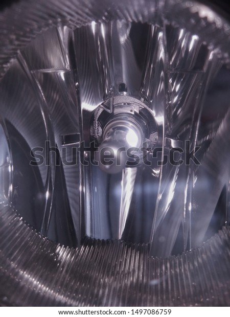 Interior\
of car headlight housing with glowing halogen lamp and ribbed\
reflector. Close-up of automobile part as abstract detail of modern\
engineering, industrial design or hi-tech\
device