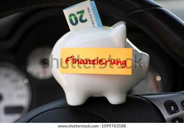 Interior of a car, piggy bank and the german word\
for credit