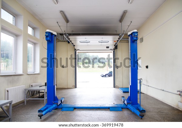 Interior of a car repair\
garage. Car lift
