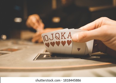 The interior of the casino. Playing cards close-up at the poker table card combination hearts Royal flush.