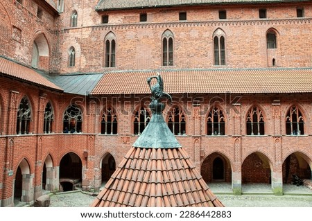 Interior castle courtyard with a well Malbork. The Castle of the Teutonic Order in Malbork by the Nogat river. Poland. Brickwork with greenery. Large brick castle wall with windows