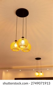 Interior ceiling lamp cluster of warm pendants suspended over communal table, golden glow creates cozy evening atmosphere