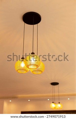 Interior ceiling lamp cluster of warm pendants suspended over communal table, golden glow creates cozy evening atmosphere