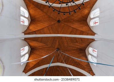 Interior of a church, focusing on the ceiling. The design features wooden panels arranged in a geometric pattern, giving it a warm and structured appearance. - Powered by Shutterstock