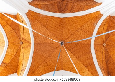 Interior of a church, focusing on the ceiling. The design features wooden panels arranged in a geometric pattern, giving it a warm and structured appearance. - Powered by Shutterstock