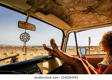 Interior of classic van camper with beautiful legs of woman stretched and relaxed. Travel people lifestyle concept. Summer holiday vacation and vanlife. Dreamcatcher and beach view holiday vacation