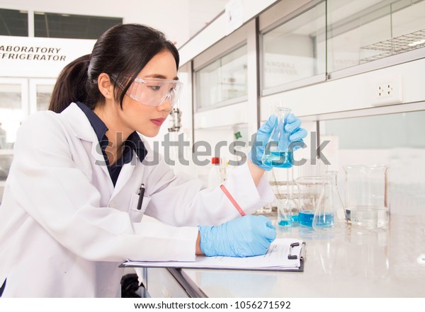 Interior of clean\
modern white medical or chemical laboratory background. Scientist\
working at lab with test tubes/flasks. Laboratory concept with\
Asian woman\
chemist/researcher.