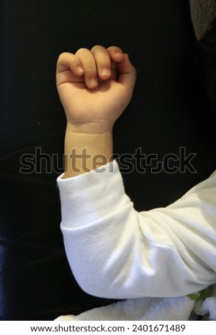 Interior close up photo view of a detail arm hand of a young baby kid child children male eurasian asian boy sleeping asleep napping resting rest on a couch sofa he is tired during his afternoon nap