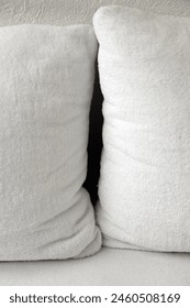 Interior close up photo view of a tiny narroe black hle space in between two 2 big large XXL soft comfortable comfort pillows